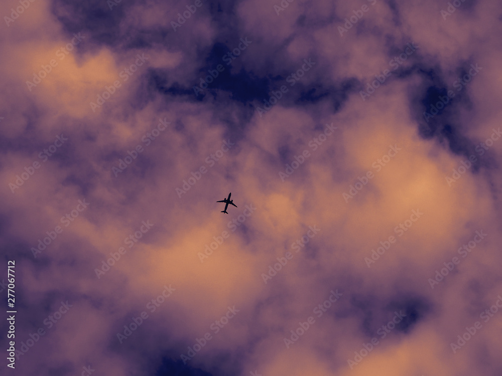 Airplane silhouette on a background of unreal colors dramatic sky and clouds. Passenger plane is flying high in the sky. Airplane silhouette on a background of unreal colors dramatic sky and clouds. Passenger plane is flying high in the sky.