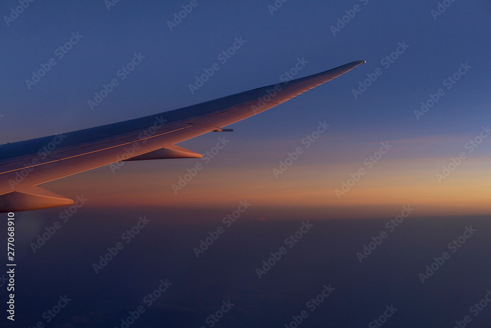 wing of airplain flying over the clouds with blue sky before sunset wing of airplain flying over the clouds with blue sky before sunset