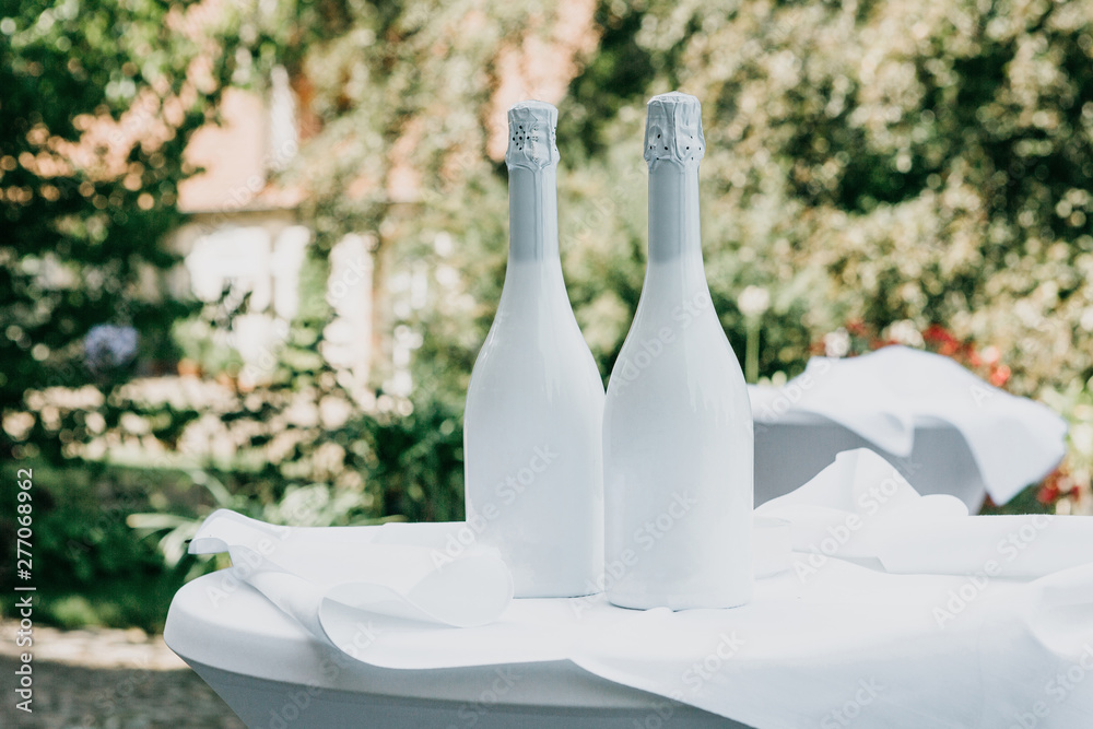 Two white champagne bottles on the table. Festive concept. - obrazy, fototapety, plakaty 