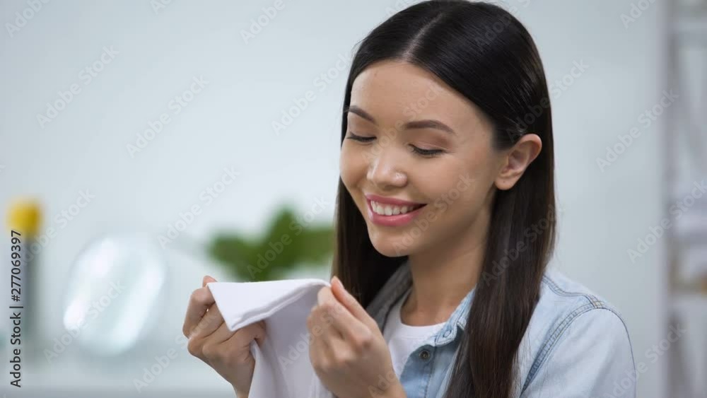 Female smelling fresh linens and smiling, enjoying fabric conditioner aroma
