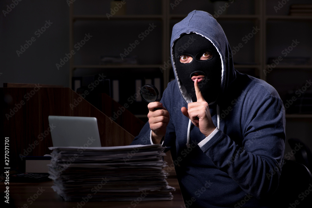 Male thief in balaclava in the office night time Male thief in balaclava in the office night time