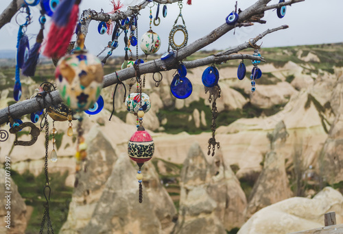 Traditional Turkish amulets and decorations hang on the branches of a wishes tree against the backdrop of the volcanic landscape of Cappadocia