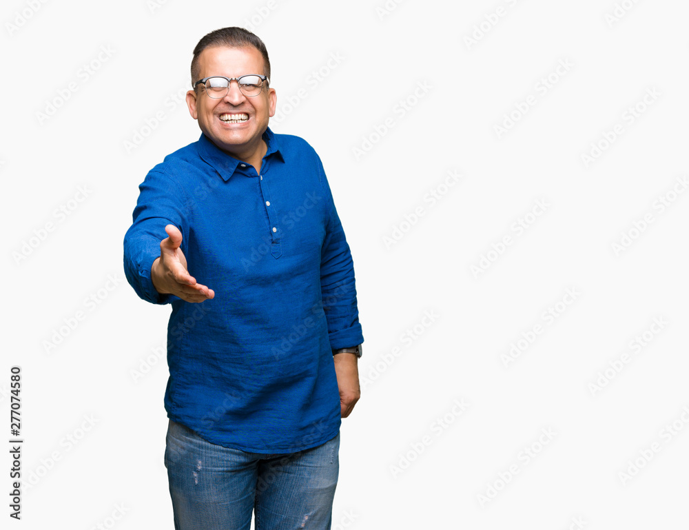 Middle age arab man wearing glasses over isolated background smiling friendly offering handshake as greeting and welcoming. Successful business. Middle age arab man wearing glasses over isolated background smiling friendly offering handshake as greeting and welcoming. Successful business.