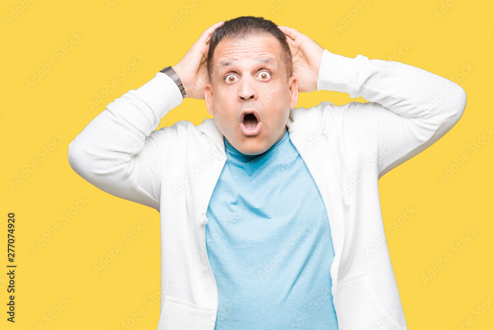 Middle age arab man wearing sweatshirt over isolated background Crazy and scared with hands on head, afraid and surprised of shock with open mouth Middle age arab man wearing sweatshirt over isolated background Crazy and scared with hands on head, afraid and surprised of shock with open mouth