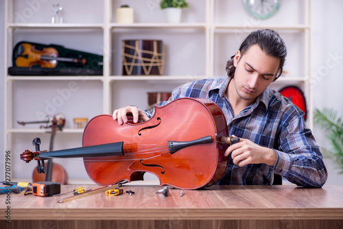 Obraz na plátně Young handsome repairman repairing violin