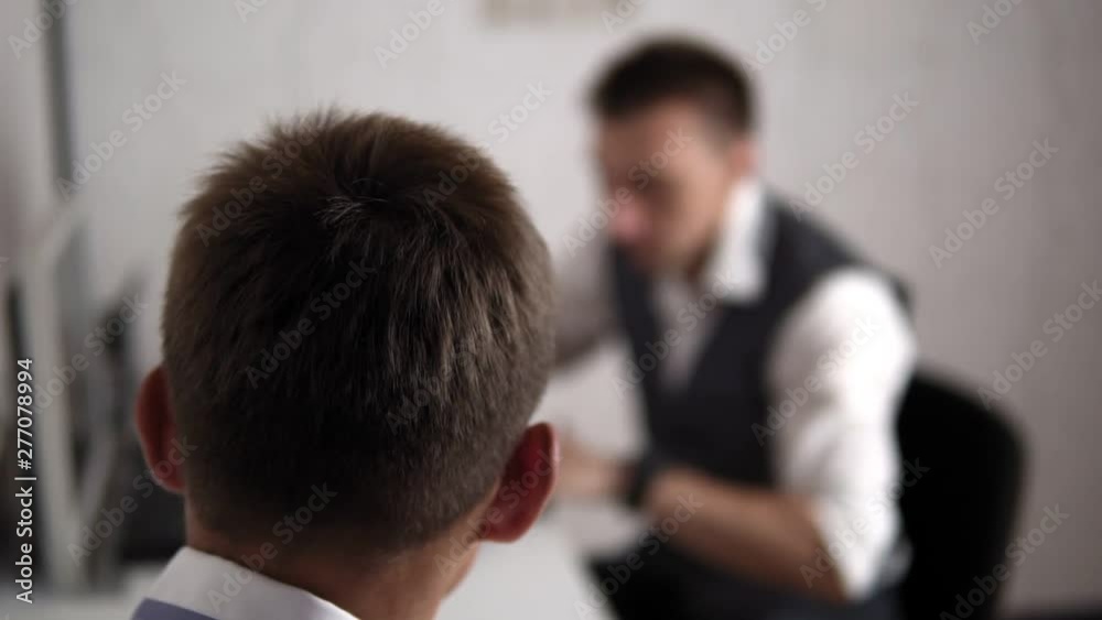 Work in police station. Detective gives signed document to subordinate sitting in office, blur video. Worker is sitting back to camera. Work in police station. Detective gives signed document to subordinate sitting in office, blur video. Worker is sitting back to camera.