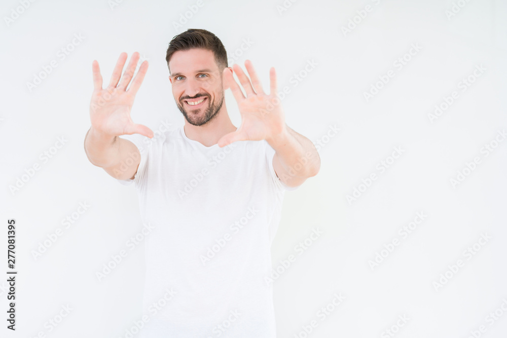 Young handsome man wearing casual white t-shirt over isolated background Smiling doing frame using hands palms and fingers, camera perspective Young handsome man wearing casual white t-shirt over isolated background Smiling doing frame using hands palms and fingers, camera perspective