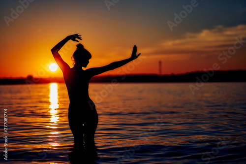 graceful girl in the water at sunset. silhouette image. summer holiday concept.