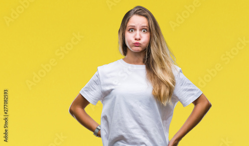 Young beautiful blonde woman wearing casual white t-shirt over isolated background puffing cheeks with funny face. Mouth inflated with air, crazy expression.