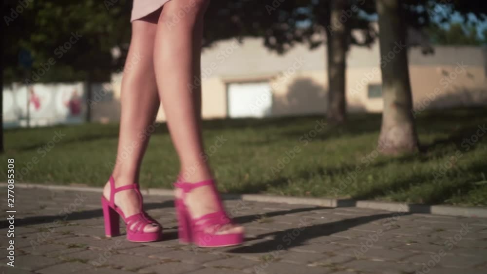 Women's legs are walking in the center of the city. Businesswoman wearing pink shoes with heels. Stylish woman walking in the city center. Women's legs are walking in the center of the city. Businesswoman wearing pink shoes with heels. Stylish woman walking in the city center.