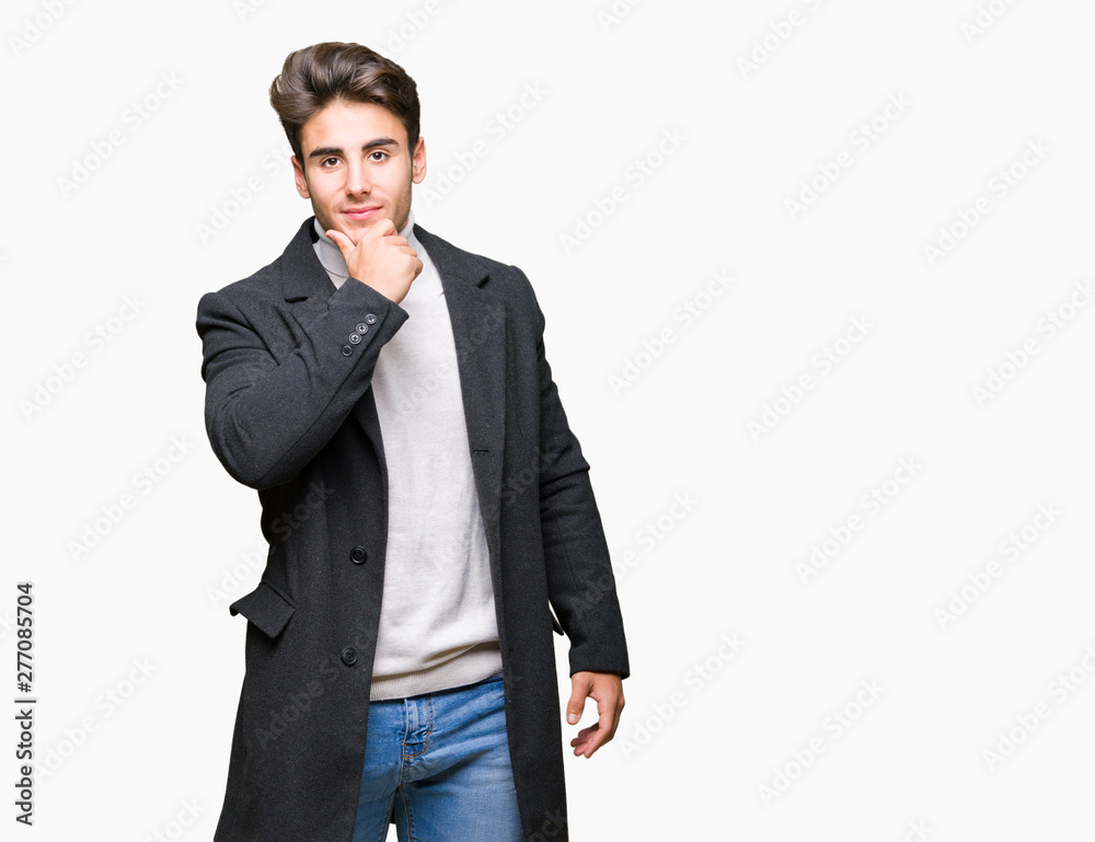 Young elegant man wearing winter coat over isolated background looking confident at the camera with smile with crossed arms and hand raised on chin. Thinking positive. Young elegant man wearing winter coat over isolated background looking confident at the camera with smile with crossed arms and hand raised on chin. Thinking positive.