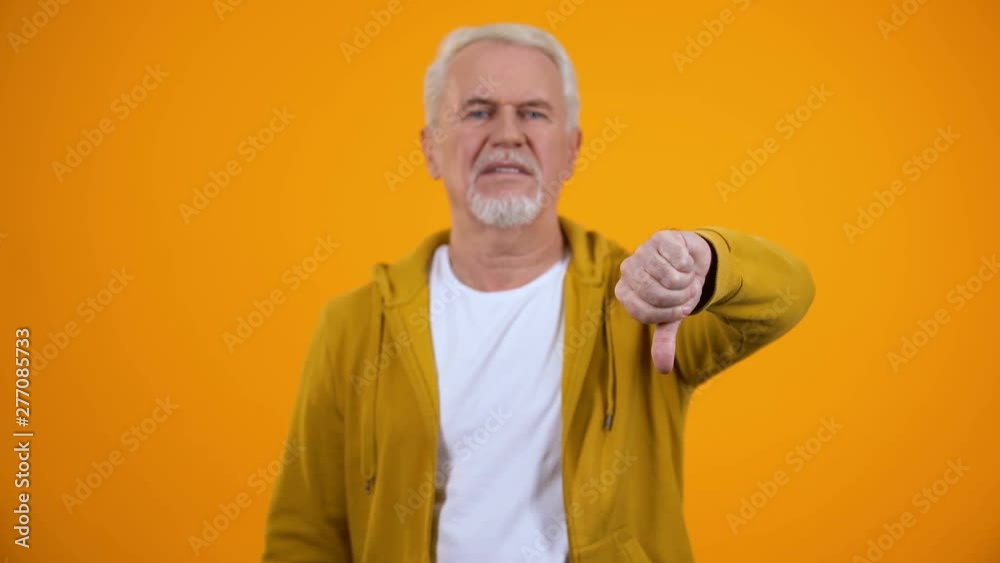 Displeased elderly man showing thumbs-down gesture, dislike, negative feedback Displeased elderly man showing thumbs-down gesture, dislike, negative feedback