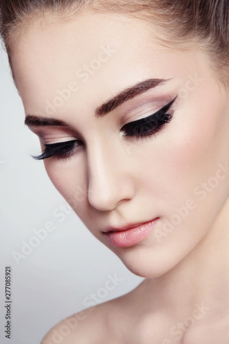 Close-up portrait of young beautiful girl with winged eye makeup