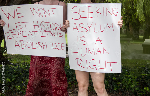 Two girls holding signs at immigration protest - We wont let history repeat itself - abolish ice - asylum - cropped and selective focus - unrecognizable