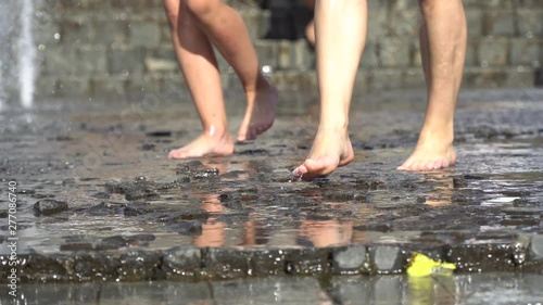 Barefoot legs play with fountain water jets. People in town play with water in the fountains, happy and carefree, concept of freedom and happiness in childhood, starting summer and tourist cities.