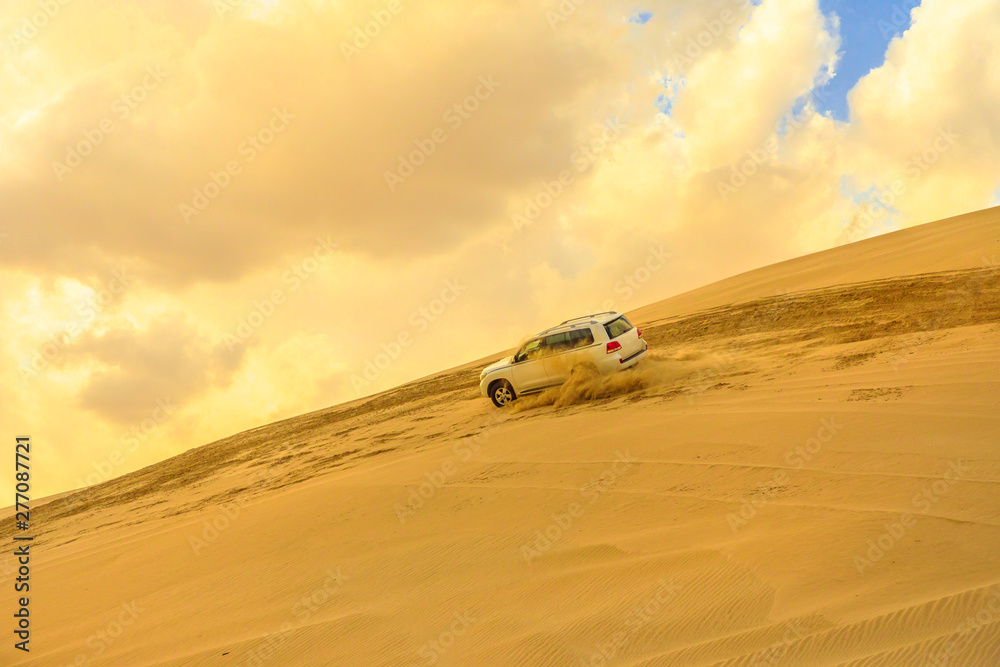Desert safari adventure. 4x4 vehicle bashing dunes side to side through the desert dunes at sunset in Qatar and Saudi Arabia. Khor Al Udeid, Persian Gulf in Middle East.