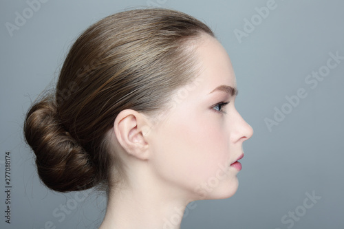 Profile portrait of young beautiful girl with hair bun
