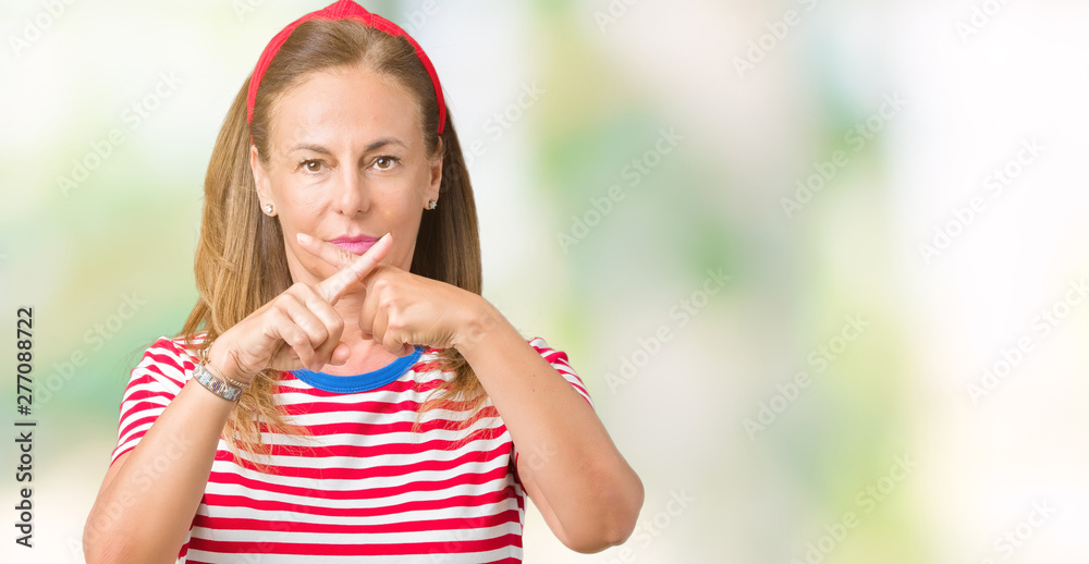Beautiful middle age woman wearing casual stripes t-shirt over isolated background Rejection expression crossing fingers doing negative sign Beautiful middle age woman wearing casual stripes t-shirt over isolated background Rejection expression crossing fingers doing negative sign