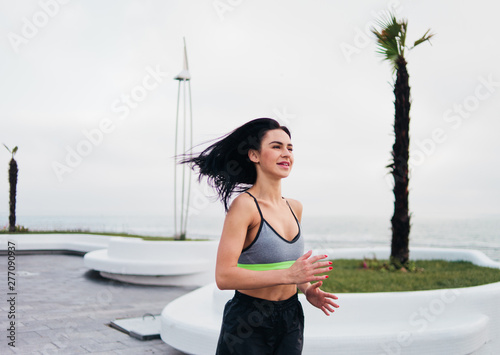 Young sport woman in sportswear run on morning beach photo