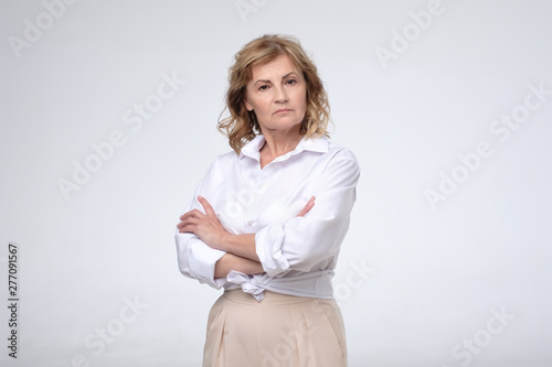 Foto Mature woman wearing white shirt standing with folded arms looking at the camera