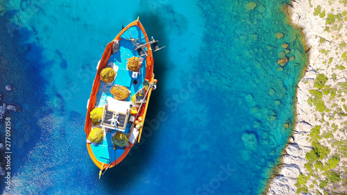 Aerial drone top view photo of red wooden traditional fishing boat in deep turquoise sea shore of Lefkada island, Ionian, Greece © aerial-drone