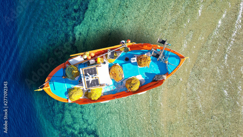 Aerial top view photo of traditonal fishing boat docked in turquoise crystal clear Ionian island sea, Greece photo