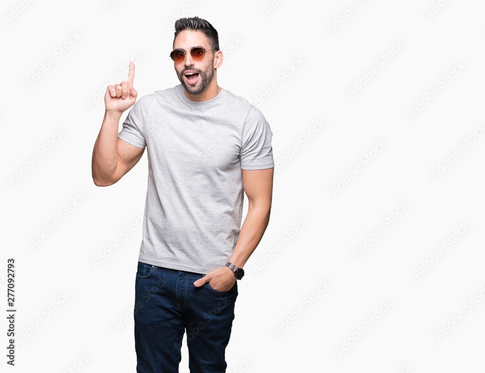 Fototapeta premium Young handsome man wearing sunglasses over isolated background pointing finger up with successful idea. Exited and happy. Number one.