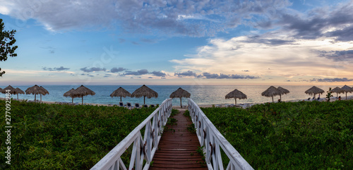 Canvas Print Beautiful panoramic view of a wooden path leading to the sandy beach on the Caribbean Sea in Cuba during a cloudy sunset