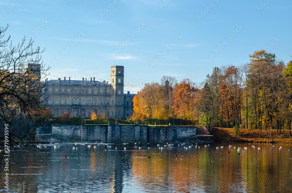 The lake with clear blue water, on the background, the walls are decorated with gold autumn trees and an ancient Palace on the other side.