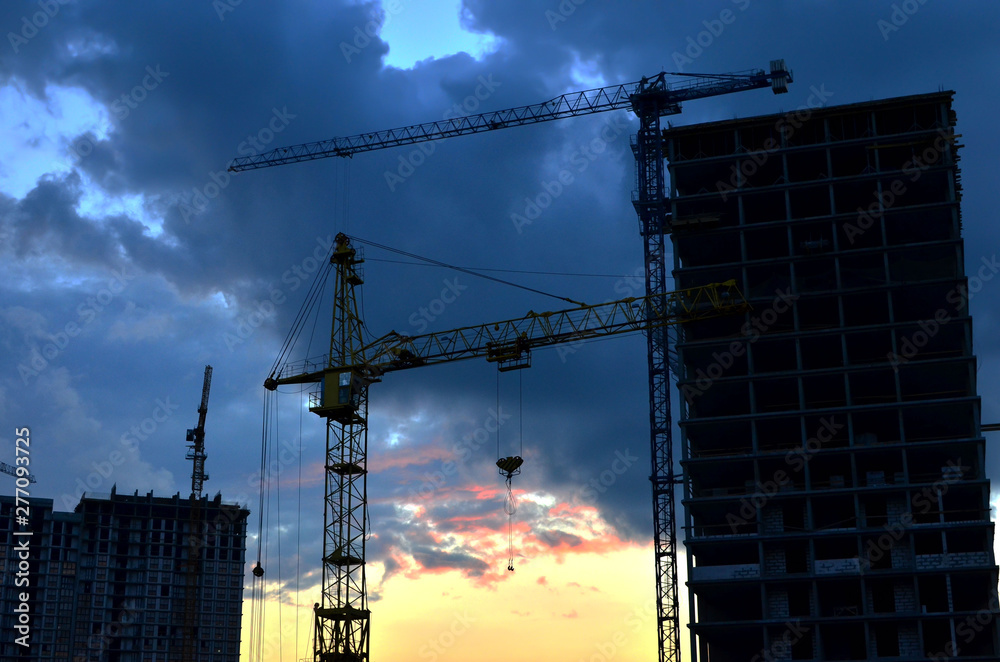 Tower cranes at construction site in the sunset sky - Image Tower cranes at construction site in the sunset sky - Image