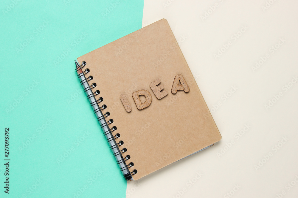 I have an idea! Notebook with craft paper with word idea on colored pastel background. Top view I have an idea! Notebook with craft paper with word idea on colored pastel background. Top view