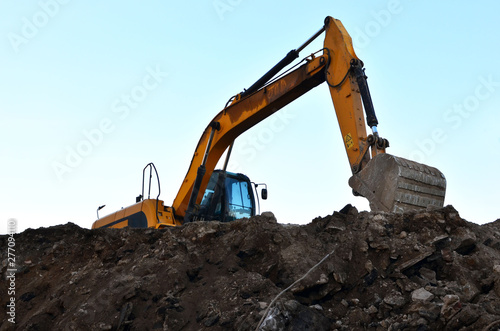 Heavy excavator working at construction site. Crushing and processing of rocks in the mining quarry. Production of building stone and crushed stone