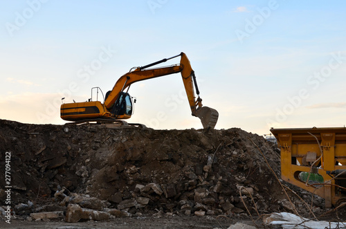 Heavy excavator working at construction site. Crushing and processing of rocks in the mining quarry. Production of building stone and crushed stone