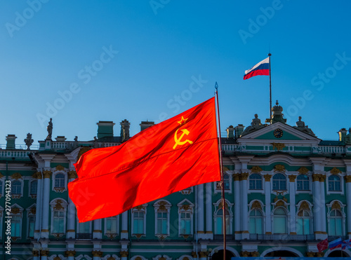 Soviet Union flag with the Russian flag and the Hermitage Museum in the background. In St. Petersburg, Russia