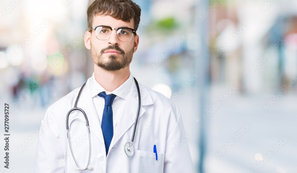 Young doctor man wearing hospital coat over isolated background Relaxed with serious expression on face. Simple and natural looking at the camera. Young doctor man wearing hospital coat over isolated background Relaxed with serious expression on face. Simple and natural looking at the camera.