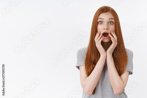 Shocked amused speechless ginger girl popping blue eyes drop jaw impressed touch face standing stunned surprised gossiping, reacting astonished hear disturbing news, white background
