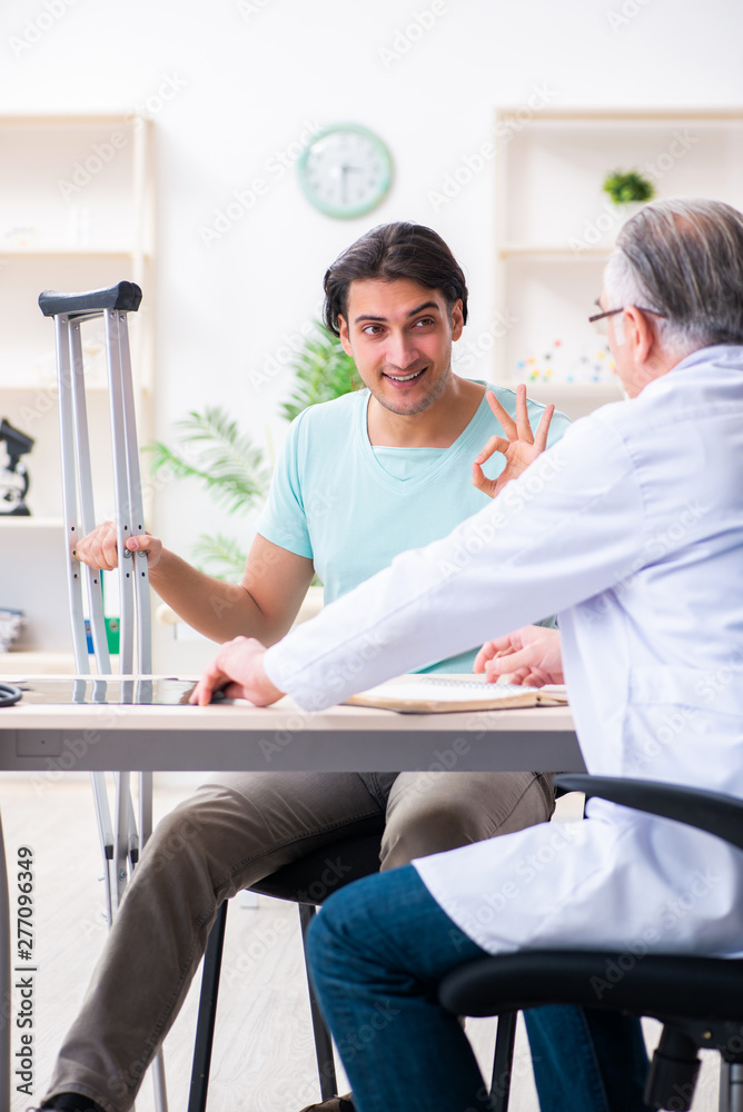 Fototapeta premium Young leg injured male patient visiting old doctor 