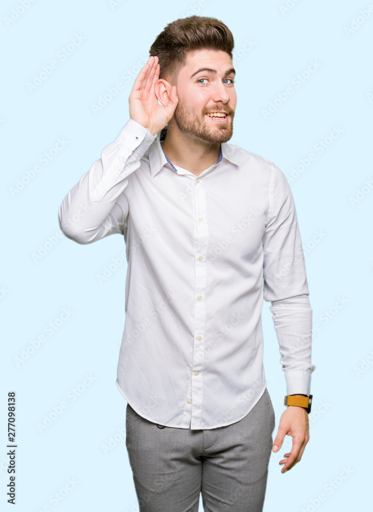 Young handsome business man smiling with hand over ear listening an hearing to rumor or gossip. Deafness concept. Young handsome business man smiling with hand over ear listening an hearing to rumor or gossip. Deafness concept.