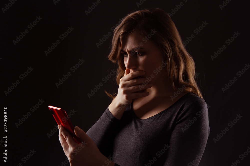 Obraz premium Girl with serious face holding phone and looking in it isolated