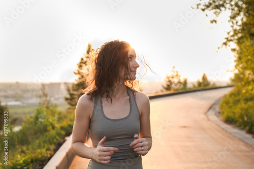 Fototapeta Naklejka Na Ścianę i Meble -  pretty slim brunette girl jogging in park in city
