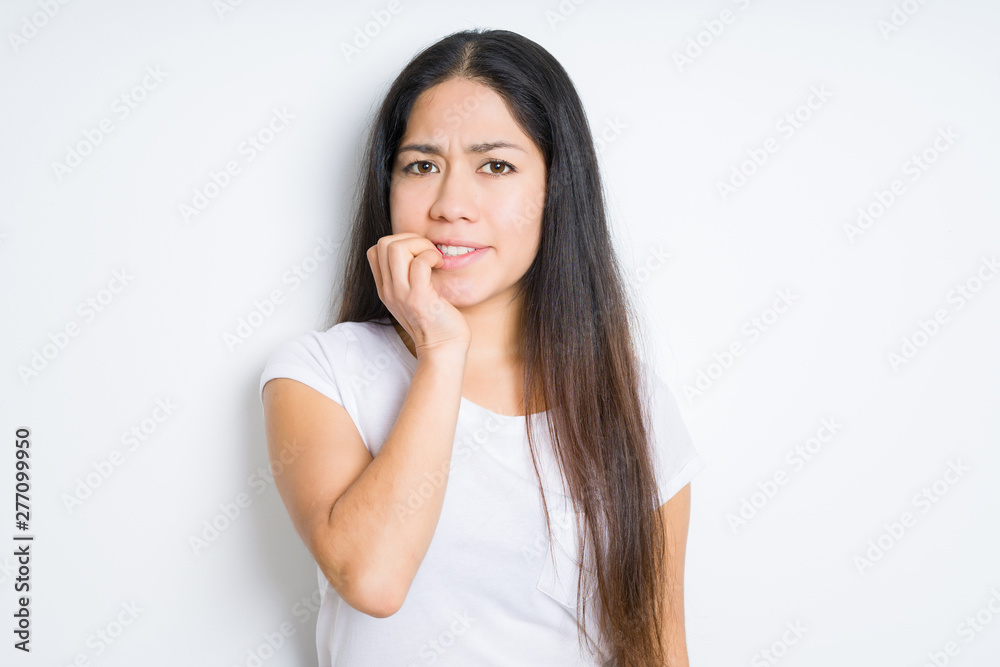 Beautiful brunette woman over isolated background looking stressed and nervous with hands on mouth biting nails. Anxiety problem. Beautiful brunette woman over isolated background looking stressed and nervous with hands on mouth biting nails. Anxiety problem.