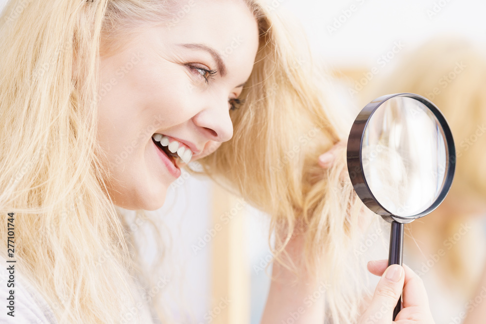 Happy woman looking through magnifer at hair Happy woman looking through magnifer at hair