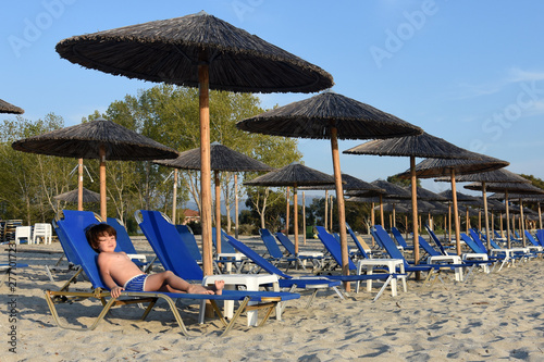 Fotografering Little boy enjoy  in deck chairs on the beach during vacations