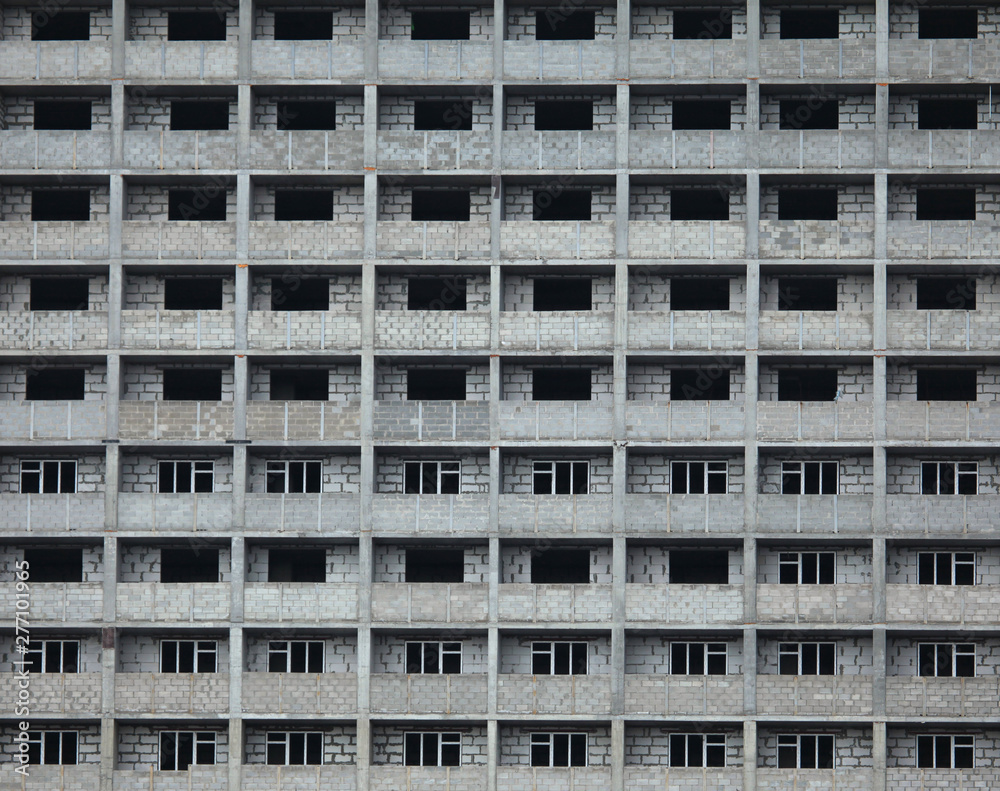 The fragment of the facade of unfinished and abandoned monolithic residential building. Background with windows of the multi-storey building