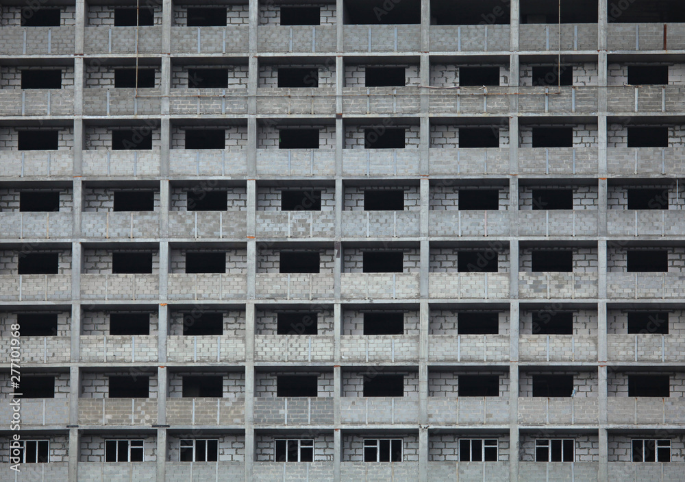 The fragment of the facade of unfinished and abandoned monolithic residential building. Background with windows of the multi-storey building The fragment of the facade of unfinished and abandoned monolithic residential building. Background with windows of the multi-storey building