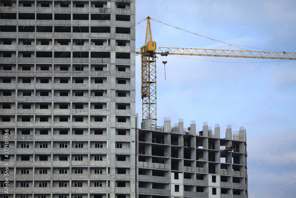 Construction site, crane and multi-storey building. Frozen building сonstruction. Unfinished and abandoned apartment monolithic residential house. Property tax