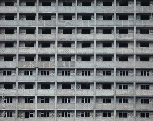 The fragment of the facade of unfinished and abandoned monolithic residential building. Background with windows of the multi-storey building