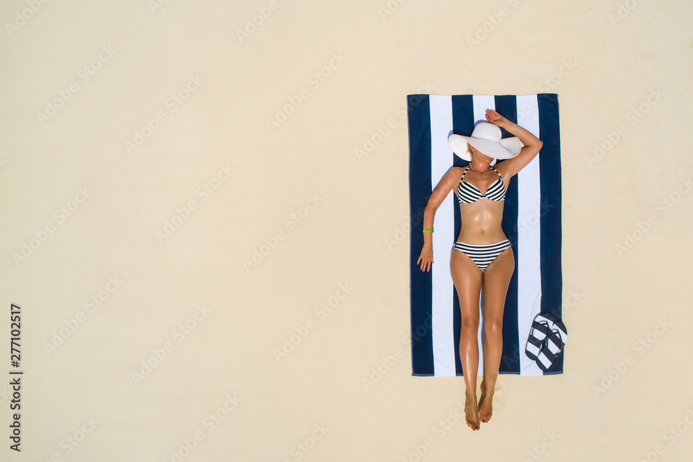 Summer holiday fashion concept - tanning girl wearing sun hat at the beach  on a white sand