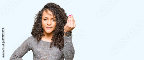 Young beautiful woman with curly hair wearing grey sweater Doing Italian gesture with hand and fingers confident expression © Krakenimages.com