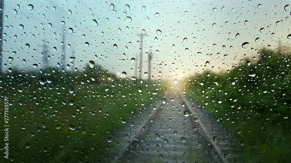 Raindrops on a window with a blurred railway road background. - obrazy, fototapety, plakaty 
